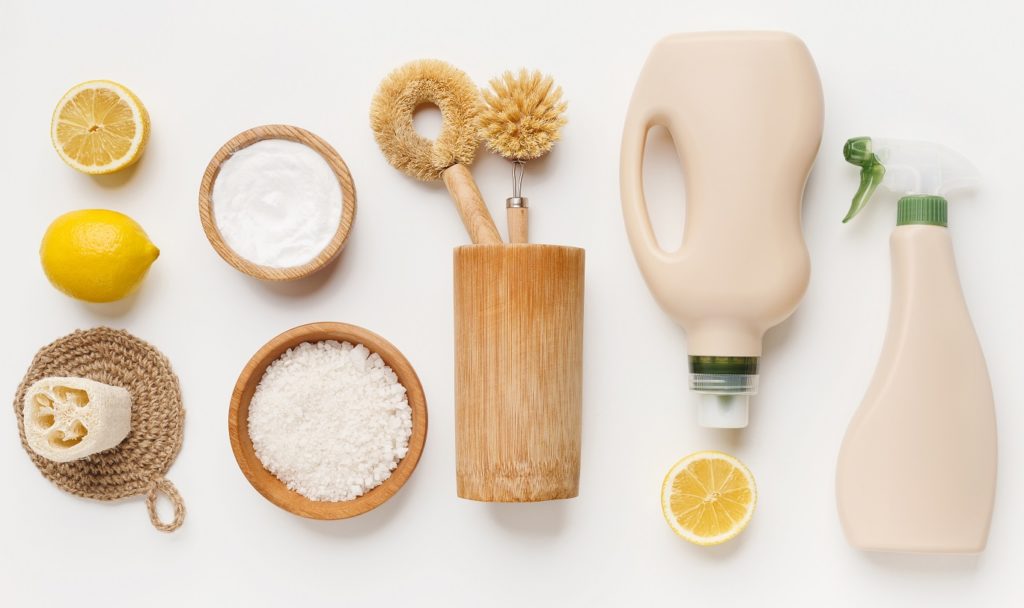Ingrédients naturels et accessoires pour la fabrication de produits ménagers zéro déchet faits maison, incluant citrons, bicarbonate et flacons.