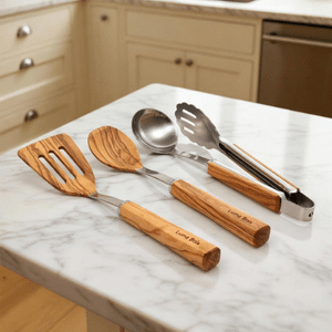 Ensemble de 4 ustensiles de cuisine en bois (spatule, cuillère, louche, pince) posés sur un plan de travail.